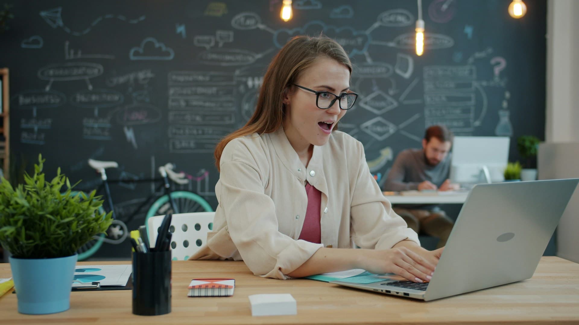 A woman excitedly using a laptop in an office setting